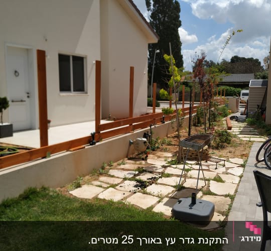 גדר עץ בבנייה ליד גינה עם צינור מים